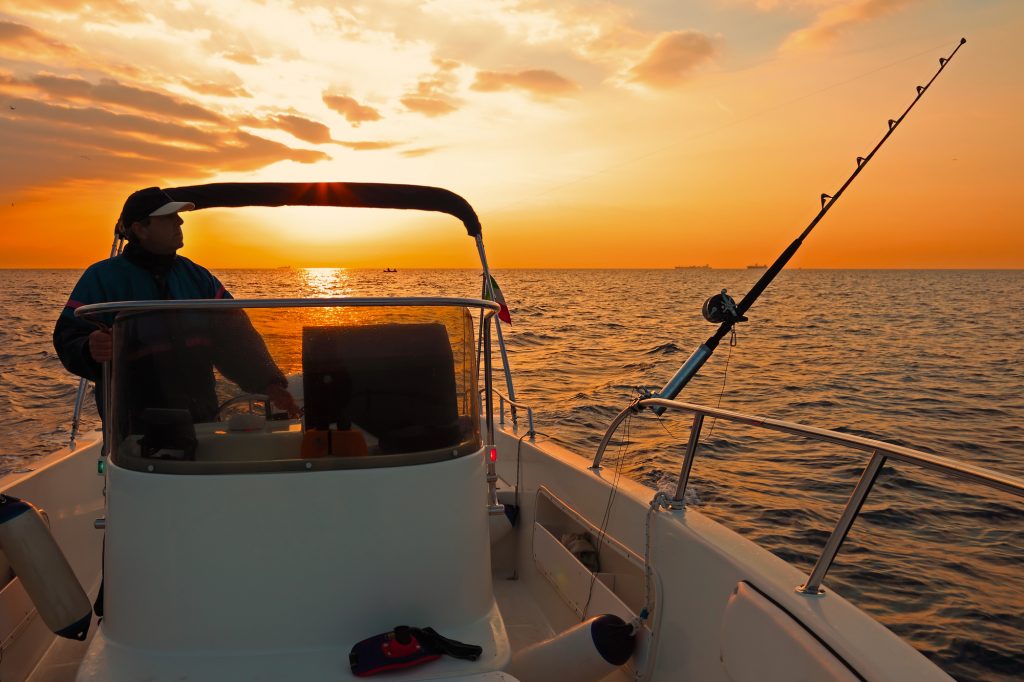 Fishing boat and fisherman in ocean at dawn