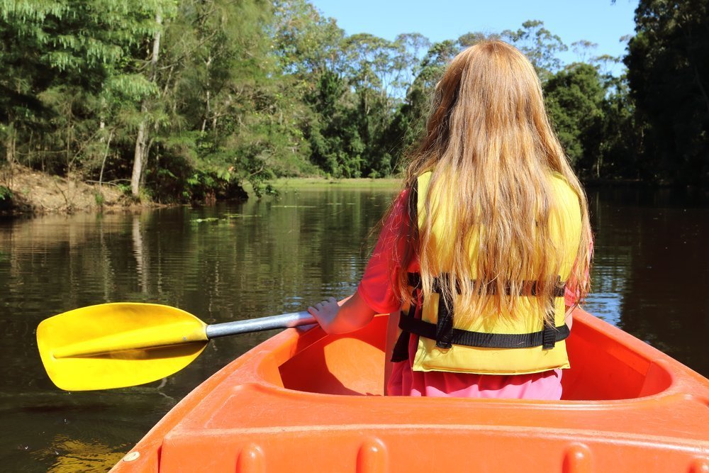 Young girl paddle in small boat and float on pond