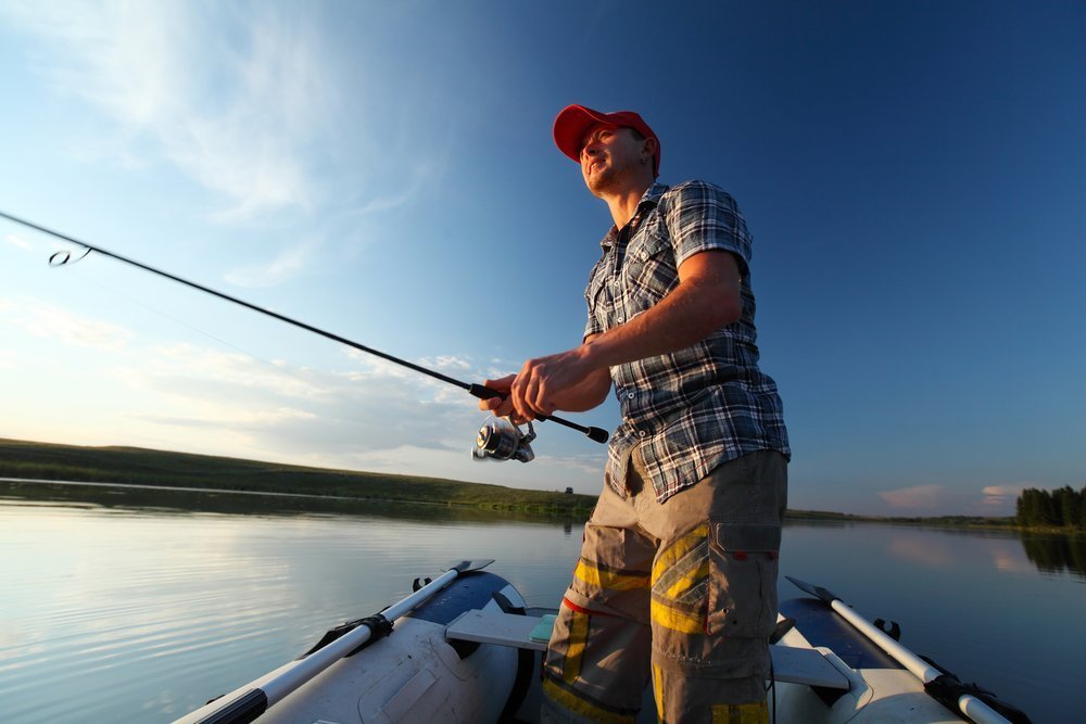 Man fishing in a pond from a boat at sunset